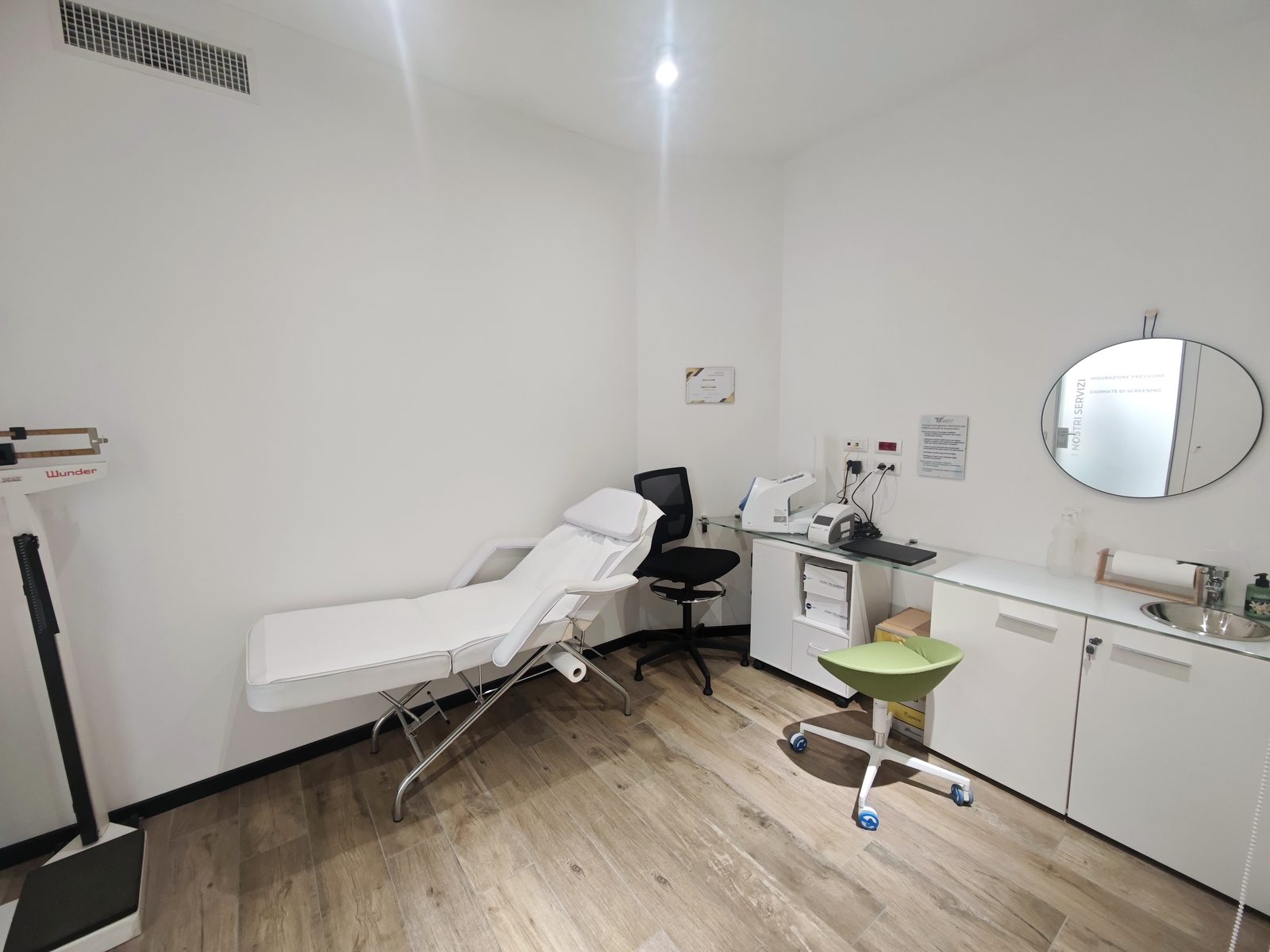 La cabina dei servizi della farmacia, con il lettino, l'elettrocardiografo e la postazione per le analisi